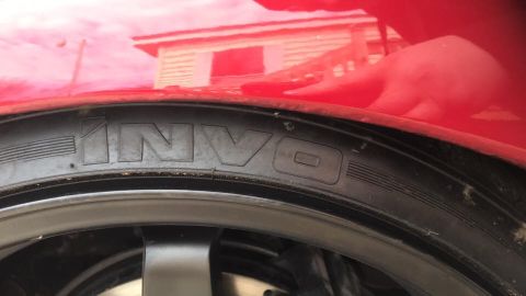 1994 Toyota Supra - Close-up of a red car's wheel well and tire, with 'INVO' visible on the tire sidewall.