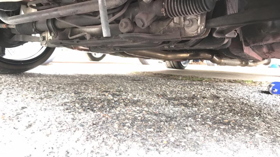 Undercarriage view showing suspension and exhaust components. Tires visible on left and right