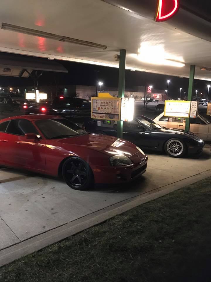 Red sports car parked at a drive-thru with another car behind it