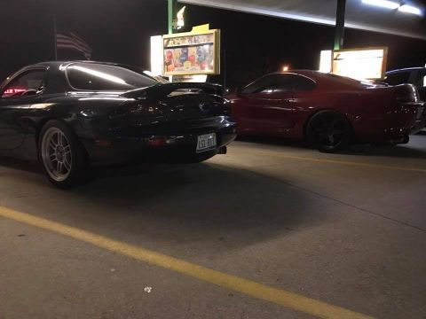 1994 Toyota Supra - A red 1994 Toyota Supra is parked next to a black car at night.