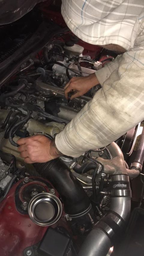 1994 Toyota Supra - Mechanic working on the engine bay of a 1994 Toyota Supra, likely performing maintenance or an upgrade.