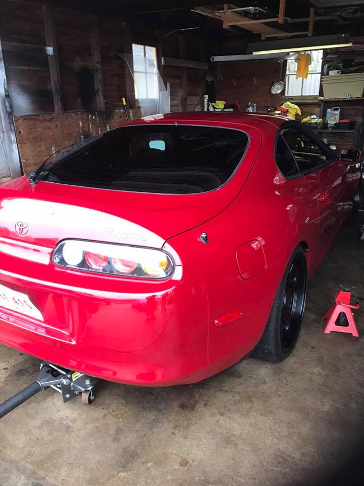 Red 1994 Toyota Supra rear view in garage, jacked up