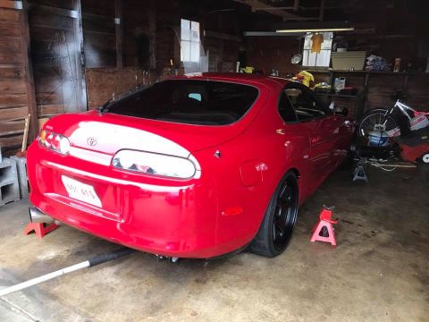 1994 Toyota Supra - Rear view of a red 1994 Toyota Supra on jack stands inside a garage.