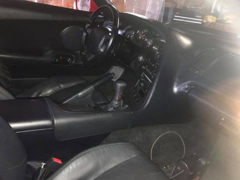 1994 Toyota Supra - The interior of the vehicle shows black leather seats, a dashboard with gauges, and a center console with a gear shifter.
