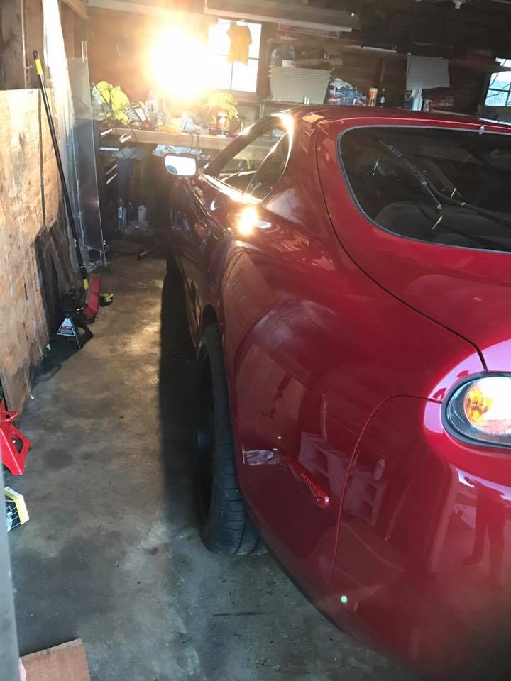 Red car rear quarter panel and taillight in a garage