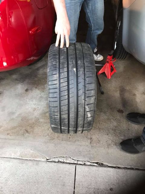 1994 Toyota Supra - A tire is shown next to a red car and a silver car in a garage setting.