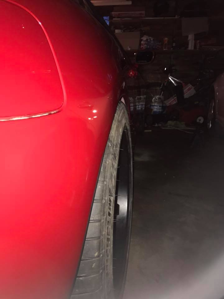 Red sports car rear quarter panel and wheel, parked in a garage