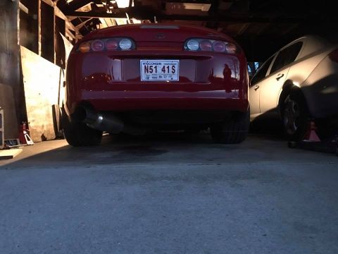 1994 Toyota Supra - Rear view of a red 1994 Toyota Supra in a garage, parked beside another vehicle.