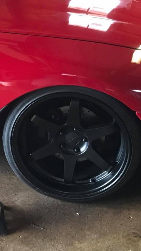 1994 Toyota Supra - Close-up of a red car's fender and a black aftermarket wheel with a visible brake rotor.
