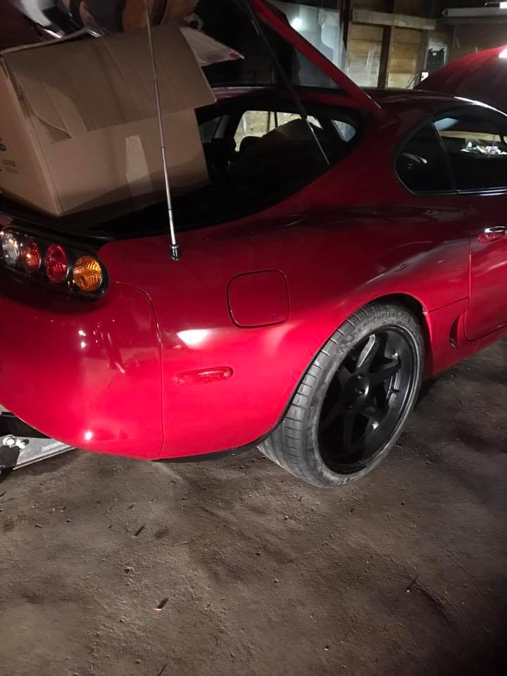 Red 1994 Toyota Supra with trunk open, showing a cardboard box inside