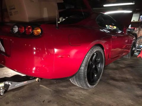 1994 Toyota Supra - The rear of a red 1994 Toyota Supra is shown, its distinctive taillights and a large spoiler.