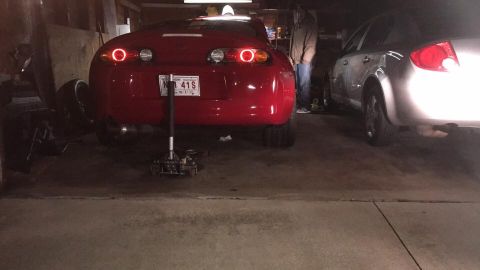 1994 Toyota Supra - The rear of a red 1994 Toyota Supra is visible, supported by a jack in a garage setting.