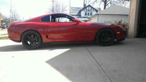 1994 Toyota Supra - Side view of a red Toyota Supra with black aftermarket wheels.