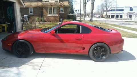 1994 Toyota Supra - A red 1994 Toyota Supra is parked outside a garage.