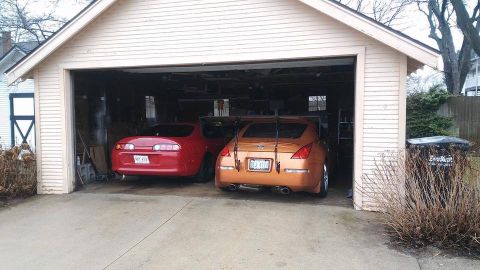 1994 Toyota Supra - A red Toyota Supra and an orange Nissan 350Z are parked side-by-side in an open garage.