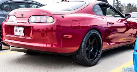 1994 Toyota Supra - The rear of a red 1994 Toyota Supra is shown, aftermarket black wheels and a custom exhaust.