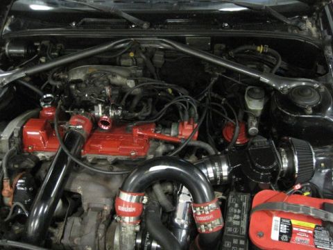 1988 Toyota Celica - A view of a modified engine bay red valve covers and prominent black intake piping.