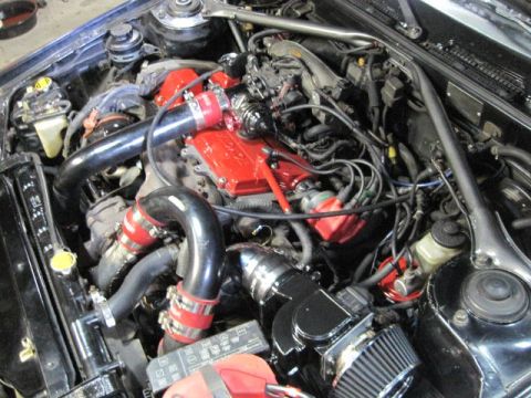 1988 Toyota Celica - Engine bay of a 1988 Toyota Celica, a turbocharger setup and custom red valve cover.