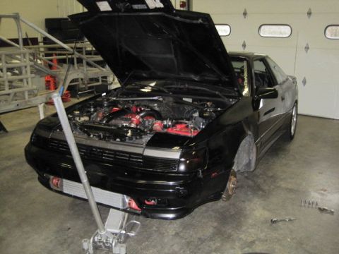 1988 Toyota Celica - A black 1988 Toyota Celica is shown with its hood open, undergoing maintenance in a garage.