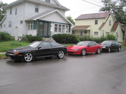 1988 Toyota Celica - Three cars are parked on a street in front of houses on a cloudy day.