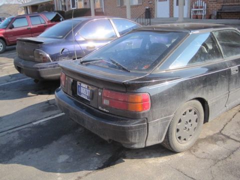 1988 Toyota Celica - A black coupe with a spoiler and a turbo badge is parked next to other vehicles.