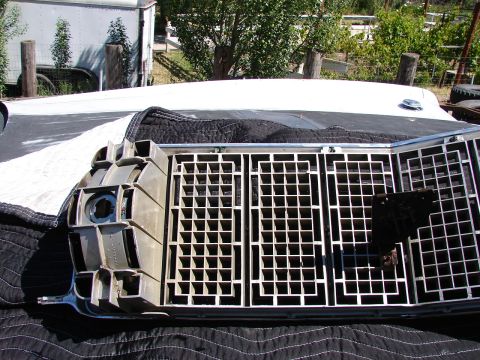 1973 Ford Ranchero - The front grille and headlight assembly of a vehicle is shown disassembled, resting on a protective cover.
