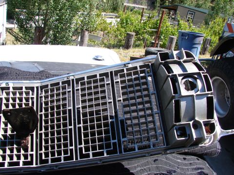 1973 Ford Ranchero - A disassembled car grille lies on a dark surface, with a white vehicle hood visible behind it.