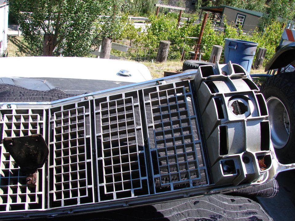 Disassembled car grille, silver, with a complex grid pattern and rectangular openings