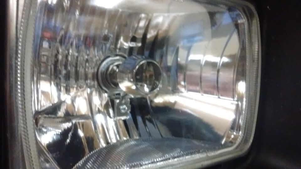 Close-up of a rectangular vehicle headlight assembly with chrome reflector
