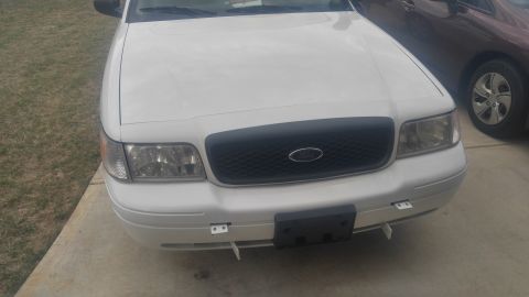 2008 Ford Crown Victoria - The front of a white Ford Crown Victoria is shown, parked next to another vehicle.