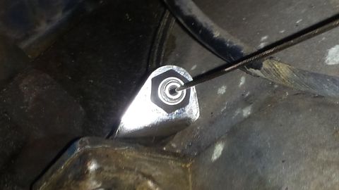 1976 Ford Ranchero - A close-up view shows a metal component of a vehicle's intake system with a cable being manipulated into place.