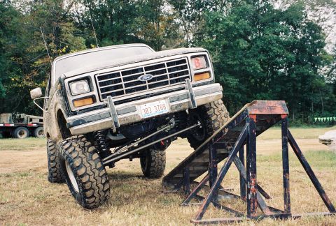 1986 Ford Bronco - A lifted Ford Bronco is positioned on a ramp, with a trailer visible in the background.