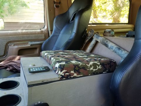 1988 Ford Bronco - The interior of the vehicle features custom bucket seats and a handmade center console with a camouflage-patterned armrest.