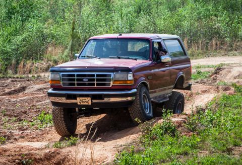 1995 Ford Bronco - 1995 Ford Bronco navigating an off-road trail with significant articulation.