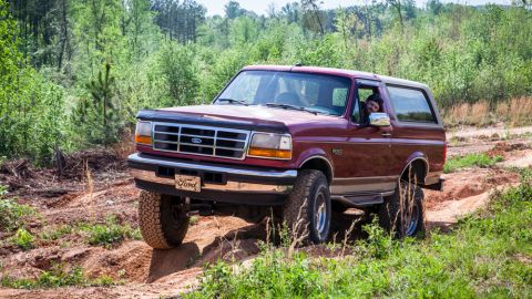 1995 Ford Bronco - A 1995 Ford Bronco navigates a rough, wooded trail.
