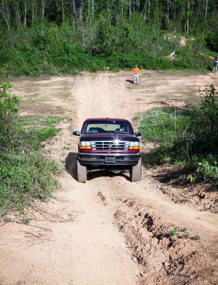 Red 1995 Ford Bronco driving on a dirt road