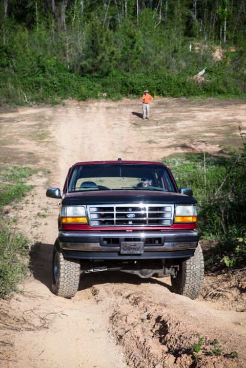1995 Ford Bronco - 1995 Ford Bronco navigates a rough dirt path outdoors.