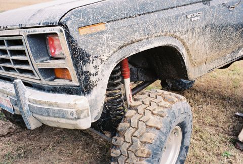 1986 Ford Bronco - Muddy 1980s Ford Bronco with lifted suspension and off-road tires.