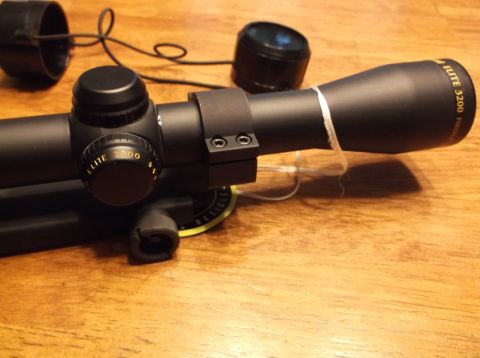 1995 Mercury Grand Marquis - A rifle scope with lens caps and mounting hardware is shown on a wooden table.