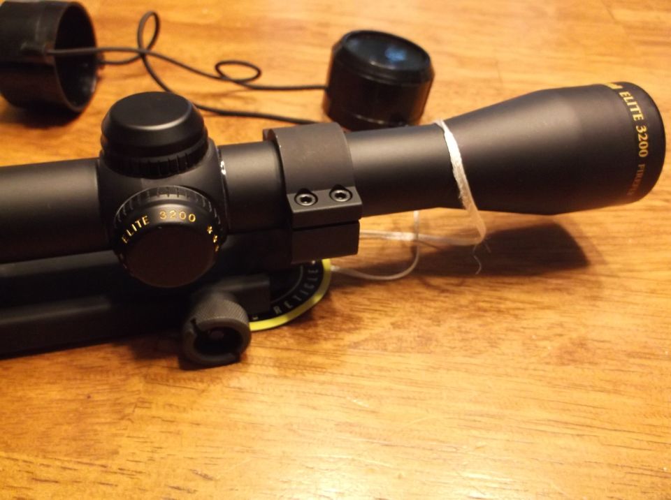 Black rifle scope with 'Elite 3200' markings, on a wooden surface