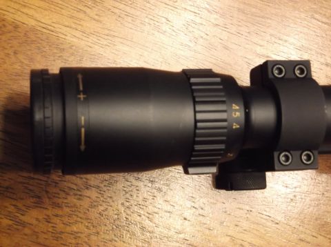 1995 Mercury Grand Marquis - Close-up of a rifle scope showing magnification and adjustment markings on a wooden surface.
