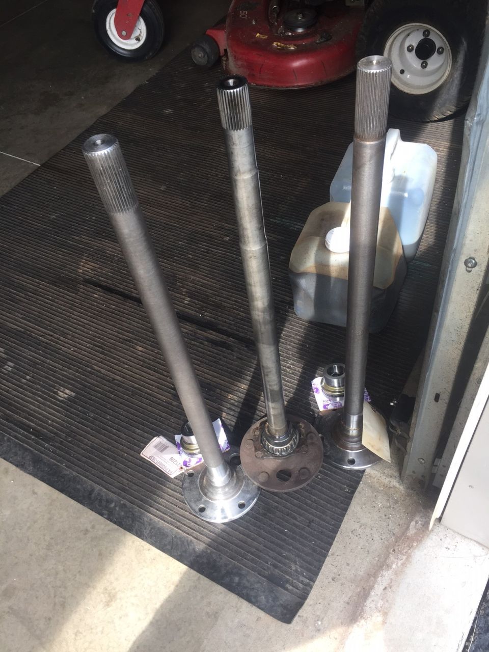 three axle shafts laid out on a mat