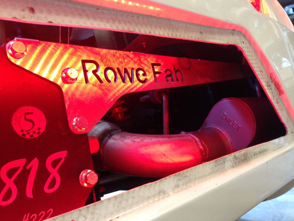 Custom exhaust pipe with 'Rowe Fab' and '818' markings, under red lighting