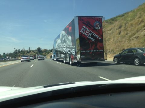 2015 Subaru Impreza - A large trailer with racing graphics is seen on the highway, alongside other vehicles.