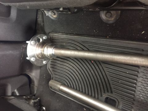 1982 Ford Bronco - Close-up of an axle shaft and hub assembly resting on a floor mat inside a vehicle.