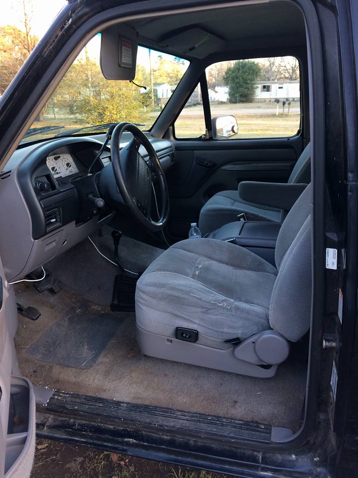 Truck interior with gray cloth seats, dashboard, and steering wheel. A water bottle is on the floor
