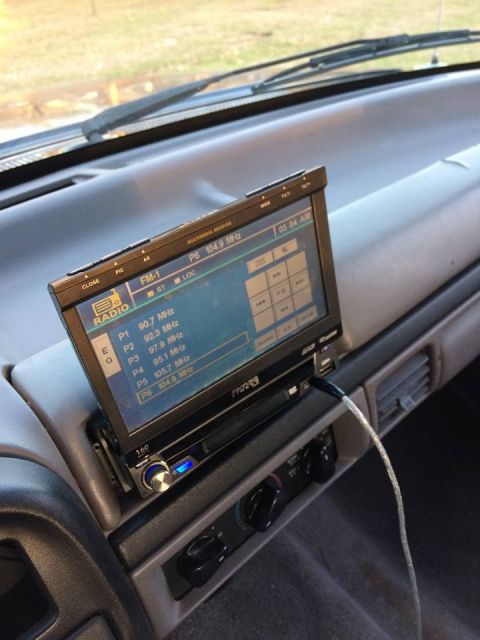 1996 Ford Bronco - The interior of a vehicle shows an aftermarket radio installed on the dashboard, displaying FM radio station presets.