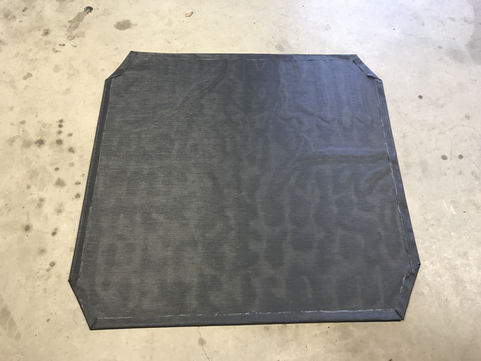 Dark gray mesh fabric with reinforced corners on a concrete floor.