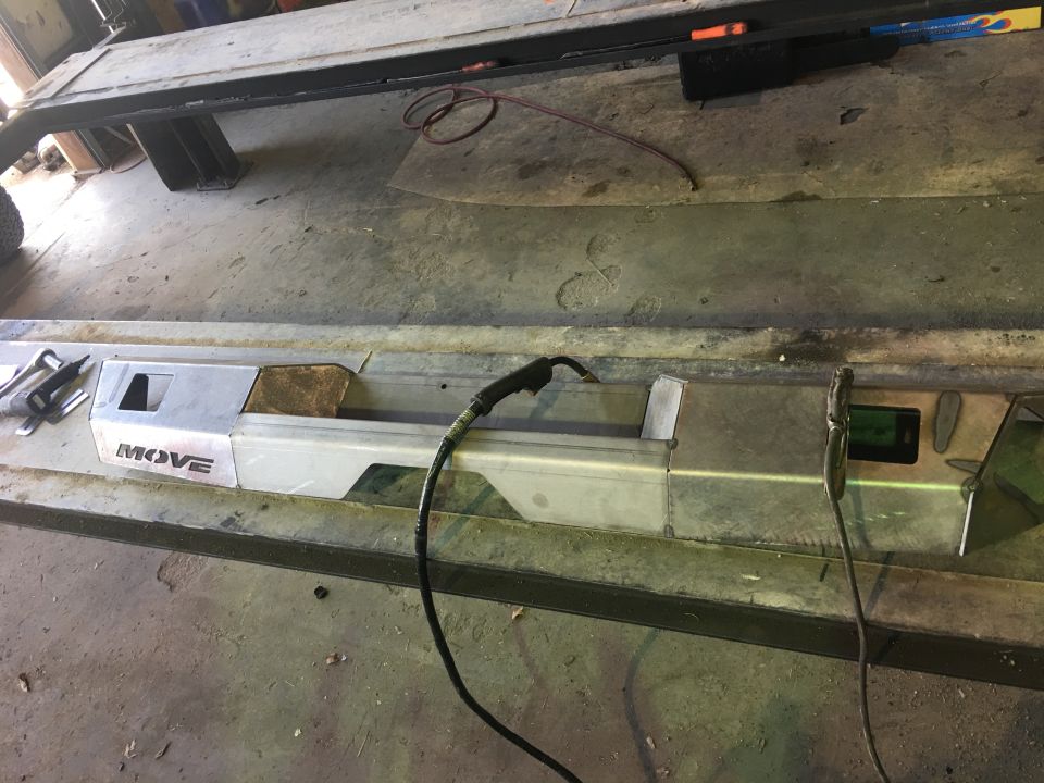 Custom metal bumper with MOVE logo being welded, on a workbench.