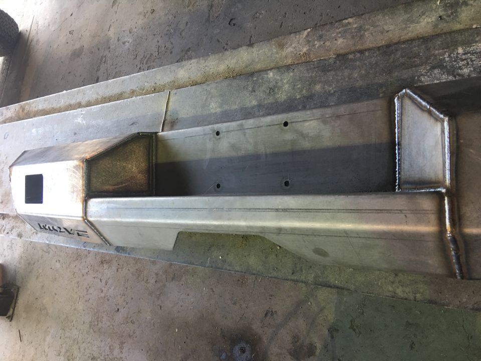 Custom metal bumper with welds and cutouts on a workbench.